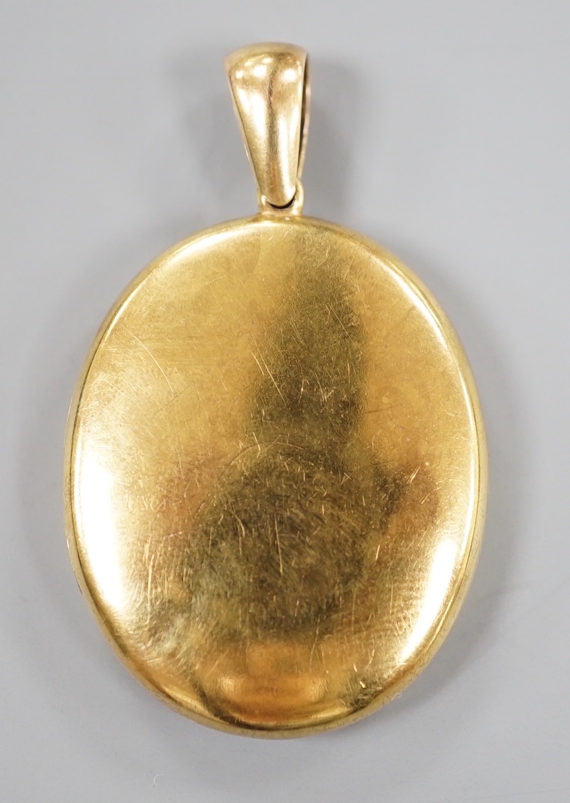 A late Victorian yellow metal oval mourning locket, containing plaited hair, overall 50mm, gross weight 14.7 grams.